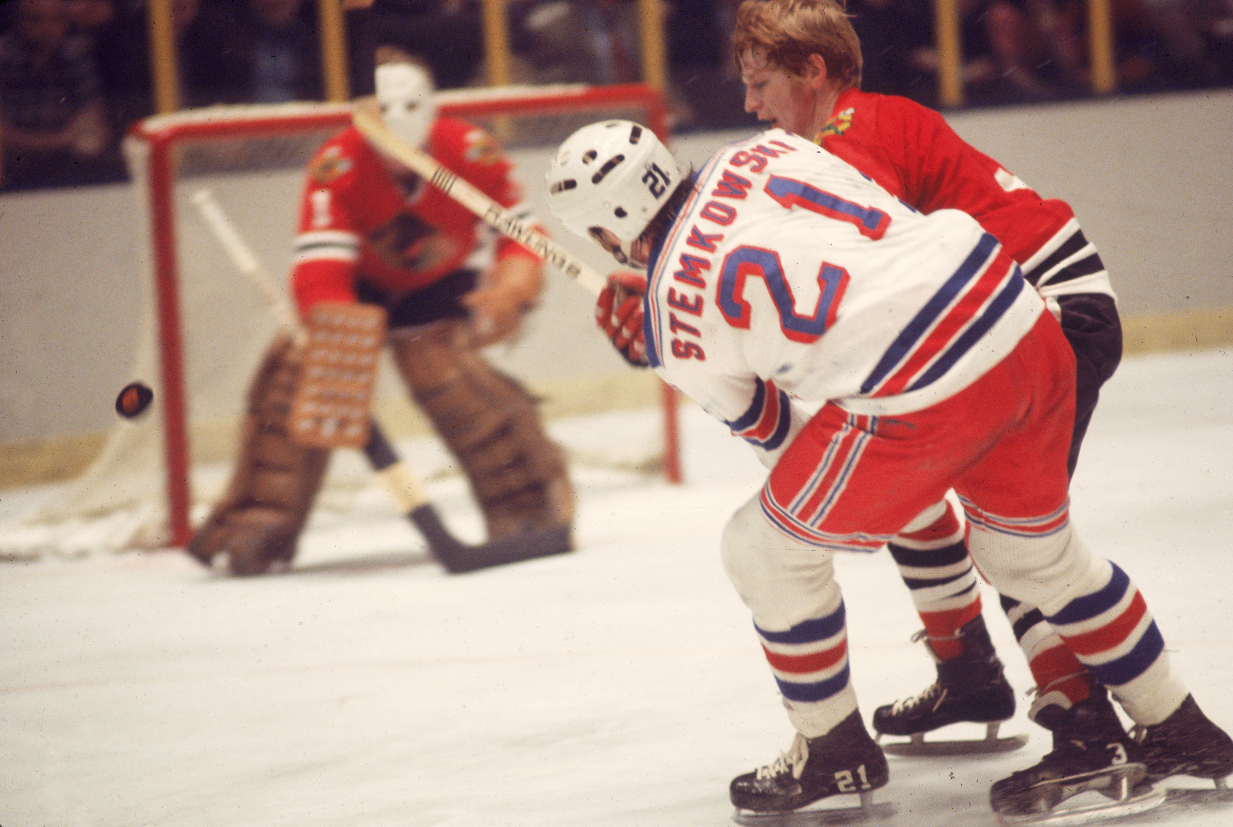 Canadian professional ice hockey player Keith Magnuson (left) of the Chicago Blackhawks checks Pete Stemkowski #21 (center) of the New York Rangers as Chicago's goalie looks on during a game at Madison Square Garden, New York, 1970s. Stemkowski played for the Rangers from 1971 to 1977. (Photo by Melchior DiGiacomo/Getty Images)